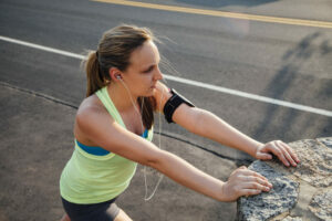 High angle view of woman wearing activity tracker stretching against concrete block